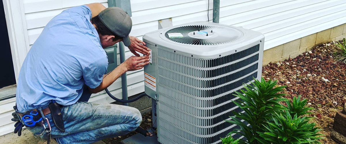 An Air Master technician performing repair on an outdoor unit